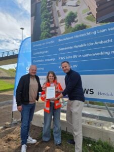 Projectleider Patrick en omgevingsmanager Gera nemen oorkonde van Mark in ontvangst 